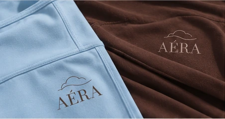 Close-up of AÉRA logos on baby blue and dark brown fabric