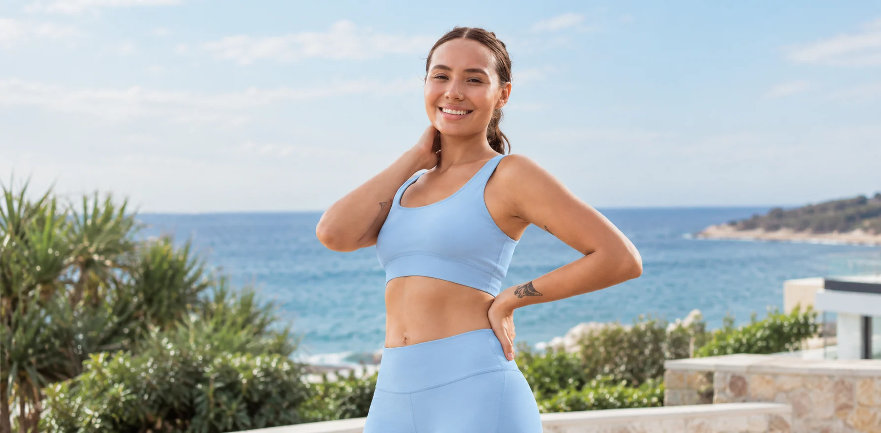 Woman in a baby blue AÉRA tank top by the sea